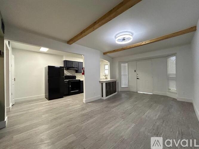 A spacious room with a black entertainment center and a wooden ceiling beam.