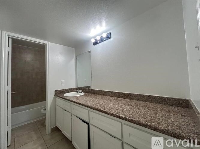A bathroom with a granite countertop and white cabinets.