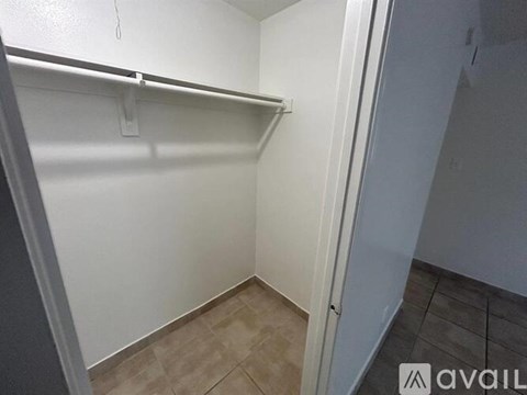 A small, empty room with a white door and a white wall.