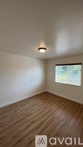 A room with wooden flooring and a window with blinds.