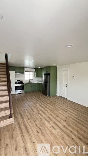 A room with wooden floors and a staircase leading to the next level.