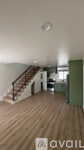 A room with wooden floors and a staircase leading to another room.