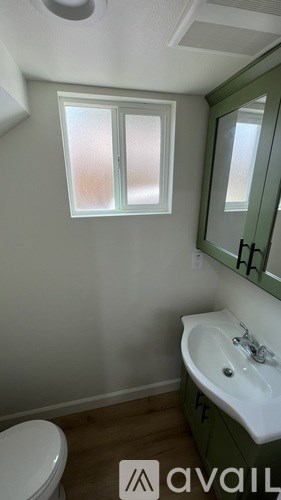 A bathroom with a toilet, sink, and mirror.
