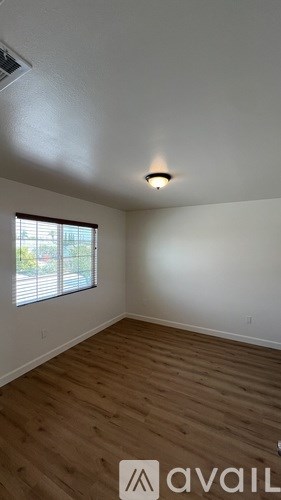 A room with wooden flooring and a window with blinds.