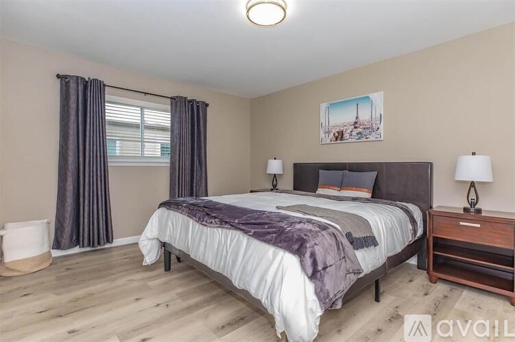 A bedroom with a large bed and a wooden nightstand.