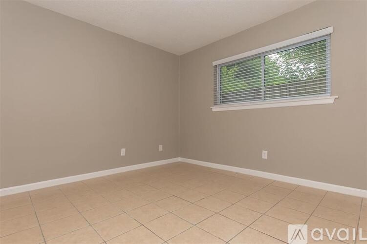 A room with beige walls and a window with blinds.