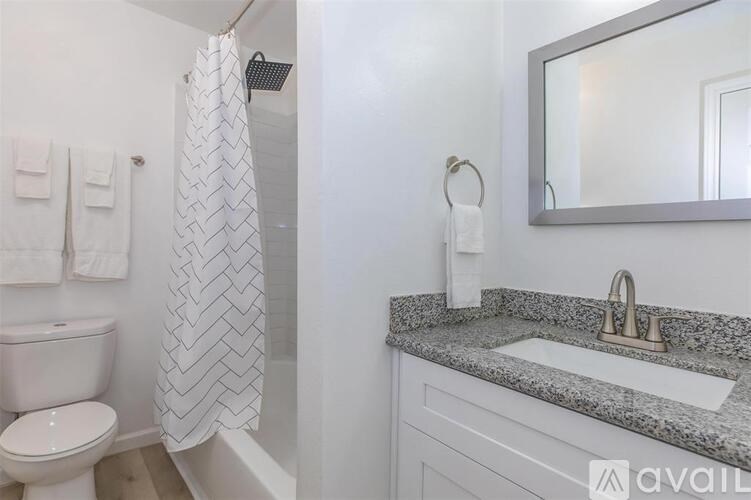 A bathroom with a white toilet, a shower curtain, a sink, and a mirror.