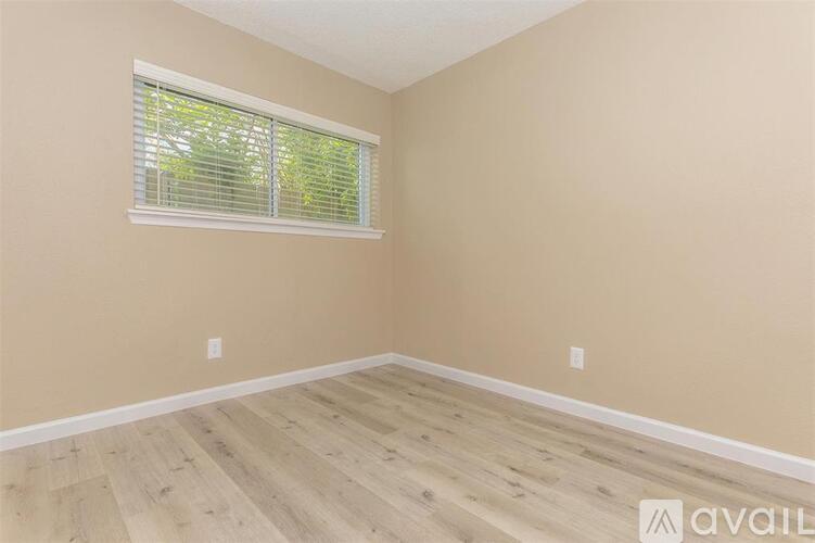 A room with wooden flooring and a window with blinds.