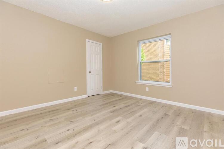 A room with wooden flooring and a window with blinds.