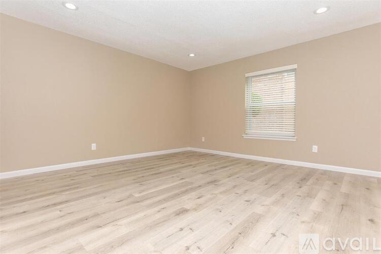 A room with wooden flooring and a window with blinds.