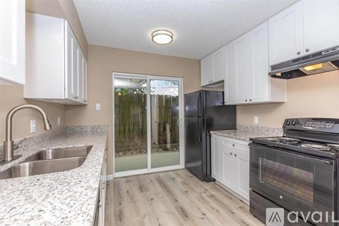 A kitchen with black appliances and white cabinets.