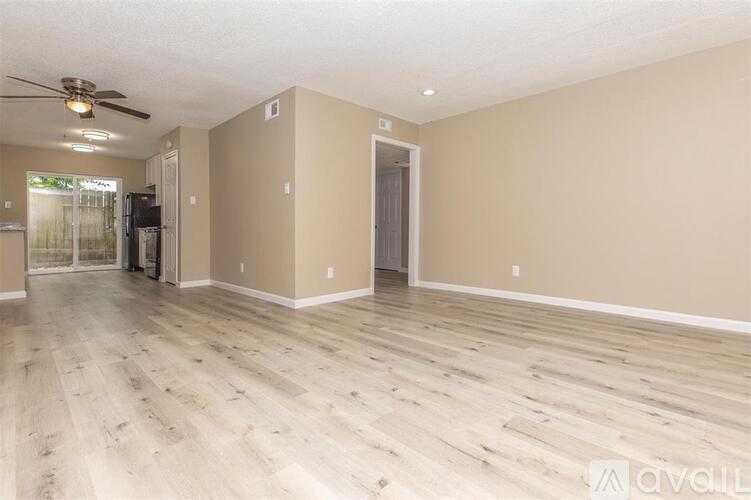 A spacious room with wooden flooring and a ceiling fan.