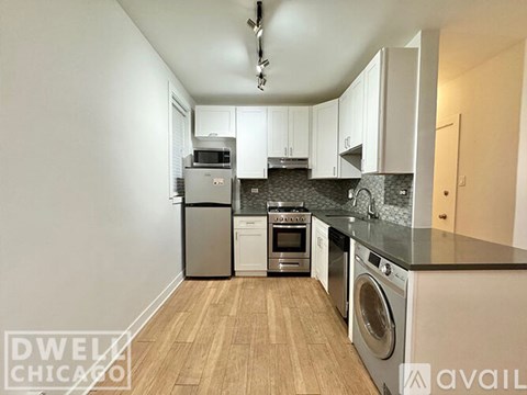 A kitchen with white cabinets and a washer and dryer built in.