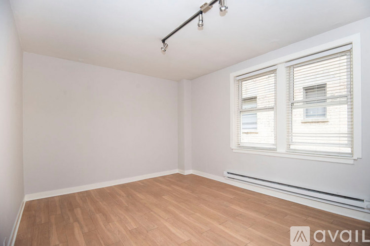 A room with wooden flooring and a window with blinds.