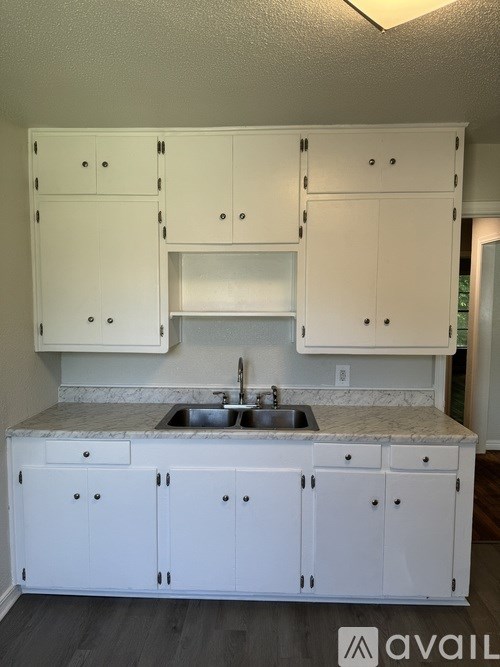 A kitchen with white cabinets and a marble countertop.