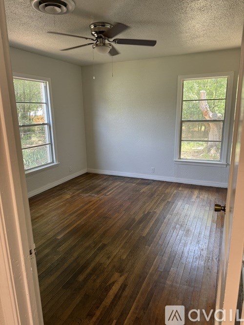 A room with a ceiling fan and wooden flooring.