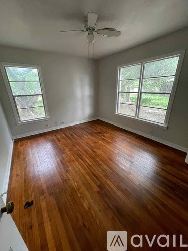 A room with wooden floors and two windows.