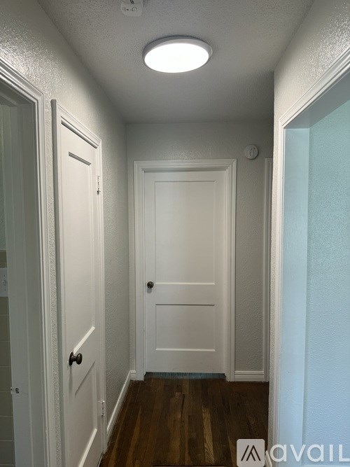 A hallway with a white door and a white wall.