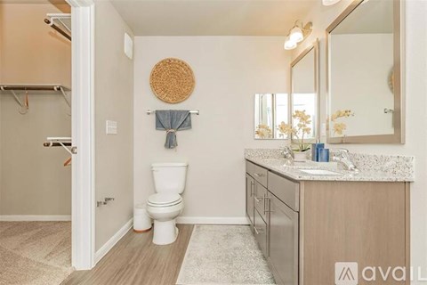 A bathroom with a toilet, sink, and mirror.