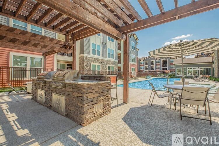 A patio with a stone fireplace and chairs under a wooden pergola.