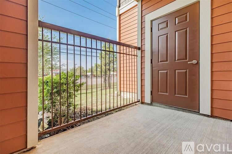 A brown door is on the right side of a balcony with a metal railing.