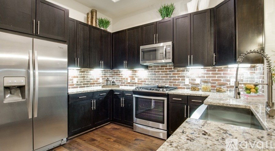 A kitchen with a refrigerator, oven, microwave, and sink.