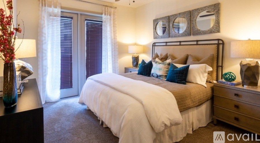 A well-lit bedroom with a large bed and a vase of flowers on the nightstand.