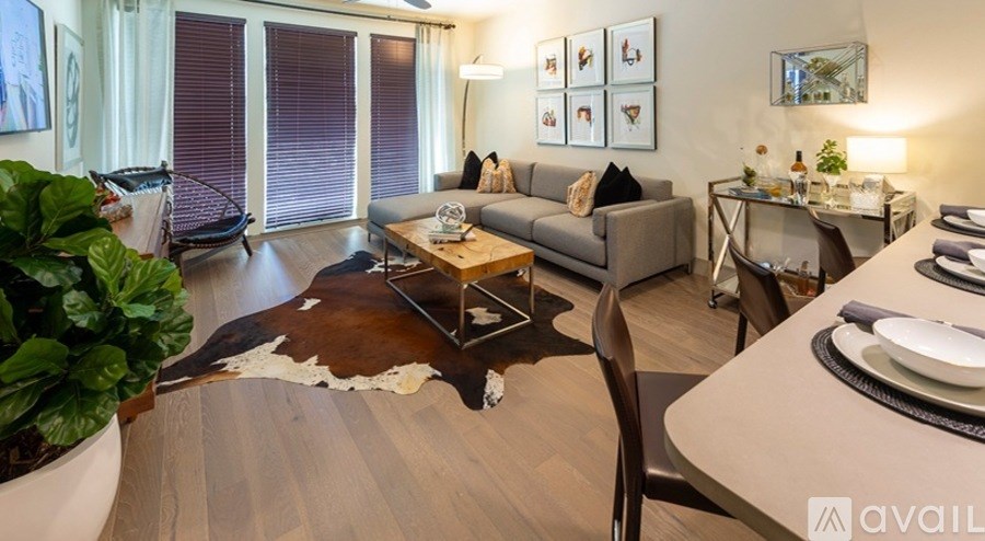 A living room with a grey couch, a brown cowhide rug, and a wooden coffee table.