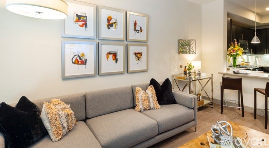 A grey couch with a pillow on it in front of a wall with pictures on it.