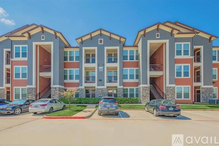 A row of modern apartment buildings with cars parked in front.