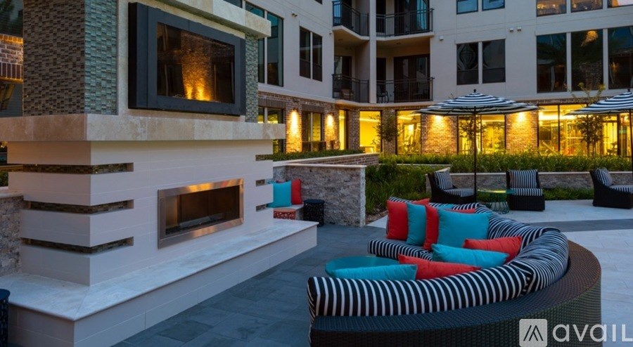A modern outdoor seating area with a fireplace and colorful cushions.
