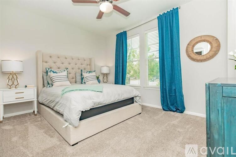 A bedroom with a large bed, a ceiling fan, and a mirror on the wall.