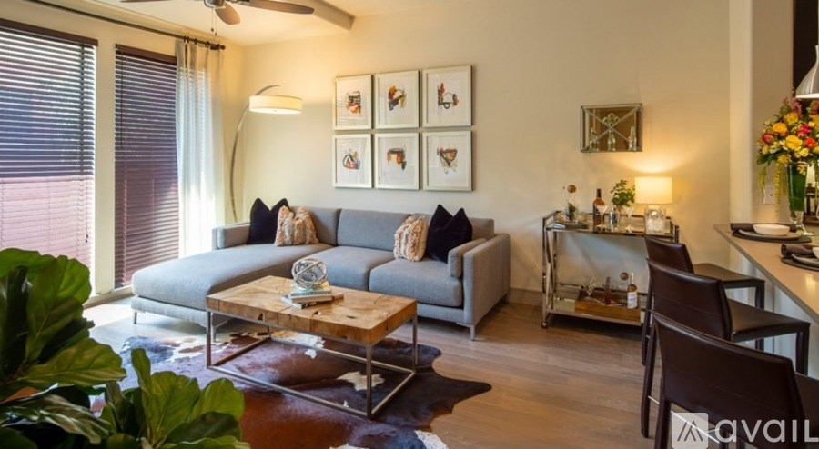 A living room with a grey couch, a wooden coffee table, and a large window with blinds.