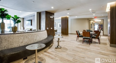 A modern living room with a curved stone wall and a dining area with chairs and a table.
