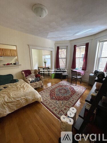 A living room with a rug on the floor and a sofa.