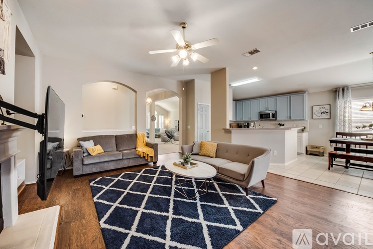 A living room with a blue rug and a television.