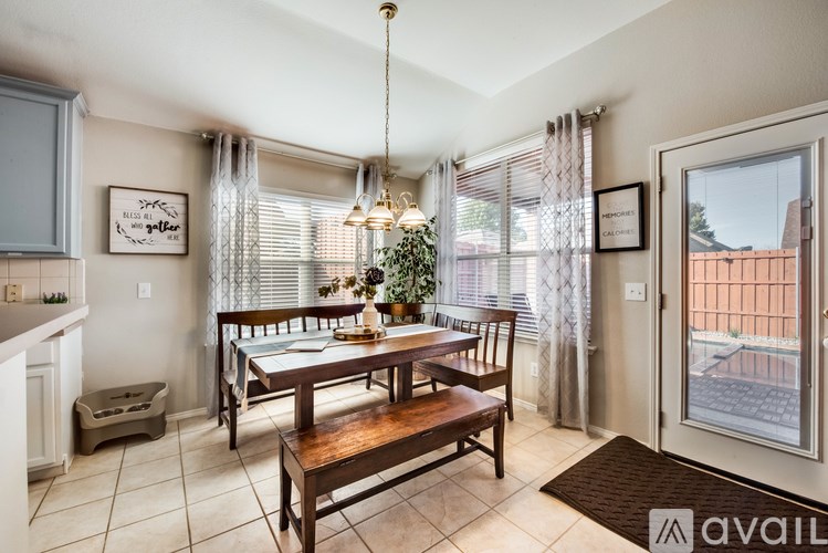 A dining room with a table set for four and a chandelier hanging from the ceiling.