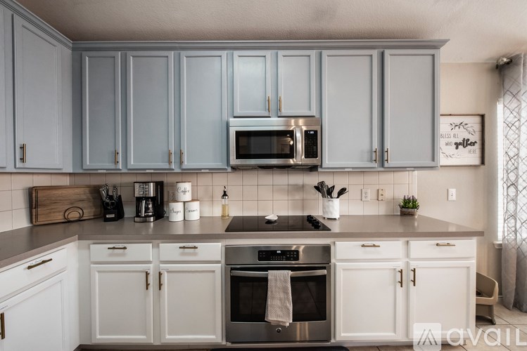 A kitchen with white cabinets and a grey backsplash.