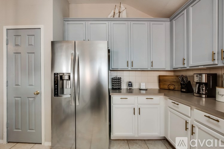 A kitchen with a stainless steel refrigerator and white cabinets.