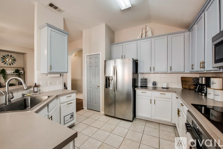 A kitchen with white cabinets and a stainless steel refrigerator.