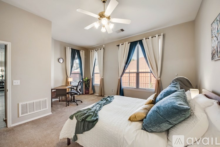 A bedroom with a large bed and a ceiling fan.