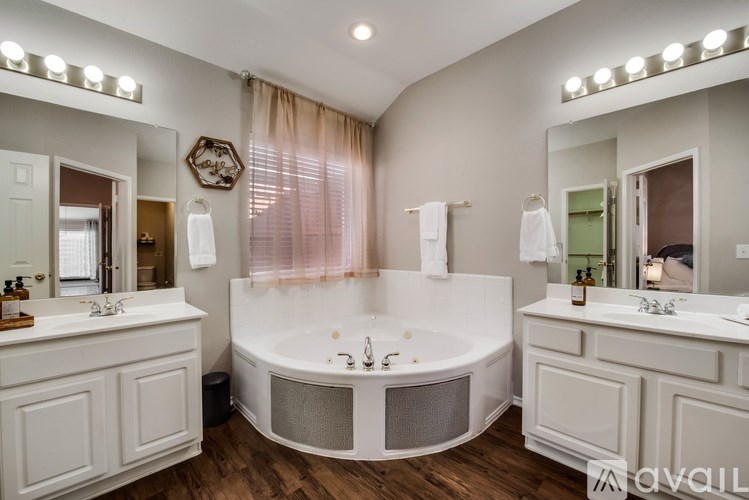 A bathroom with a white tub and a large mirror above the sink.