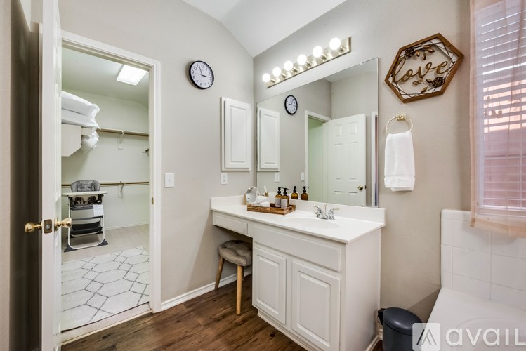 A bathroom with a vanity, mirror, and a clock on the wall.