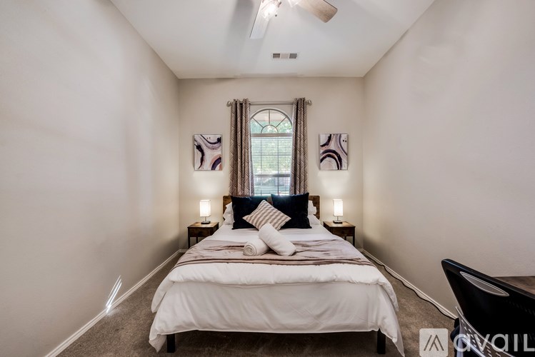 A bedroom with a large bed and a window with curtains.