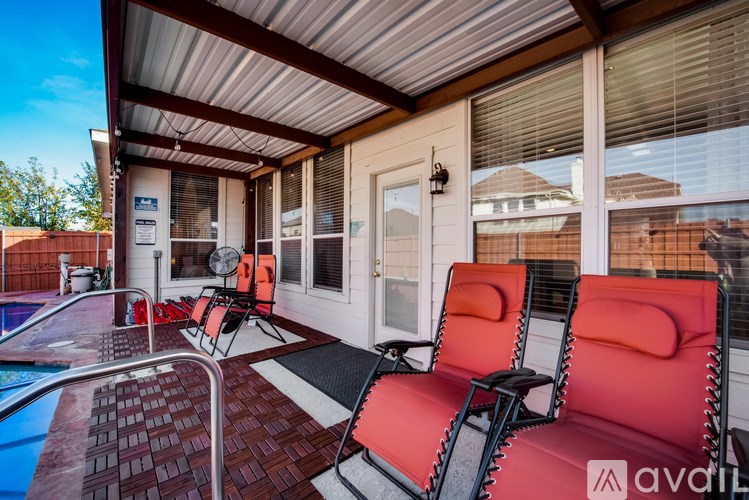 A patio with a pool and red chairs.