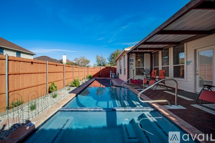 A pool in a backyard with a fence and a house in the background.