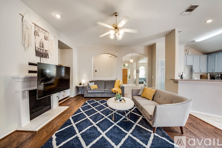 A living room with a television, a couch, and a rug.
