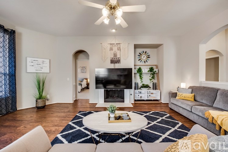 A living room with a white ceiling fan and a grey couch.