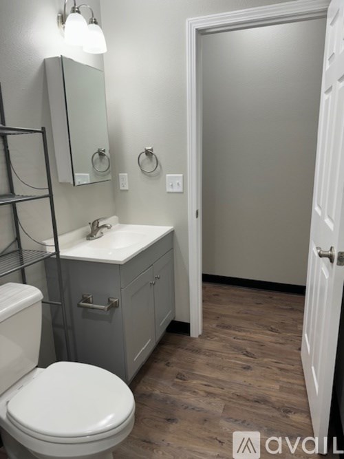 A bathroom with a toilet, sink, and mirror.