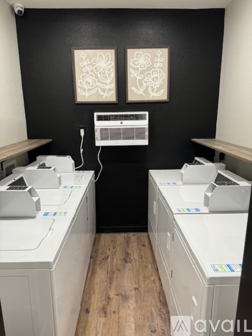 Two white copiers are in a room with wood floors and two framed white flowers on the wall.